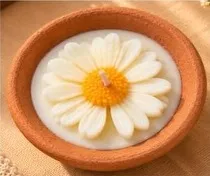 A terracotta bowl candle with a white daisy