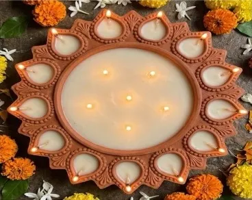 A large terracotta diya-shaped candle surrounded by marigolds
