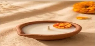 A single terracotta diya candle on sand