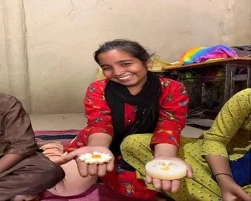 A woman artisan smiling as she shows the candles she made